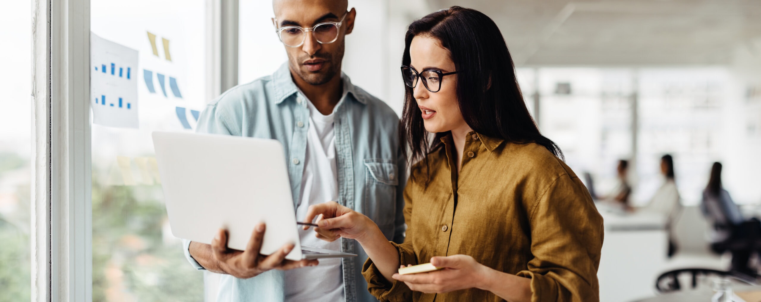 business people standing in an office and using a laptop